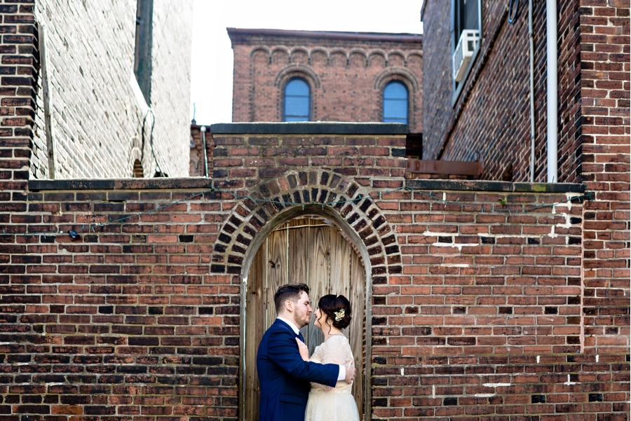 A newly married couple kiss in the doorway on the Philadelphia sidewalk.